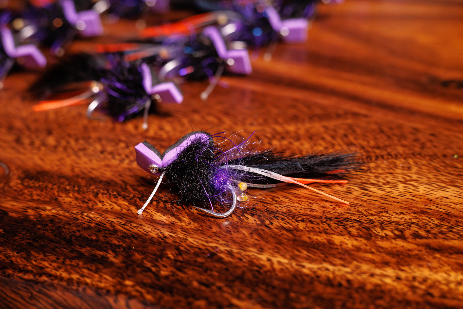 Purple and black fly fishing lure on a wooden surface